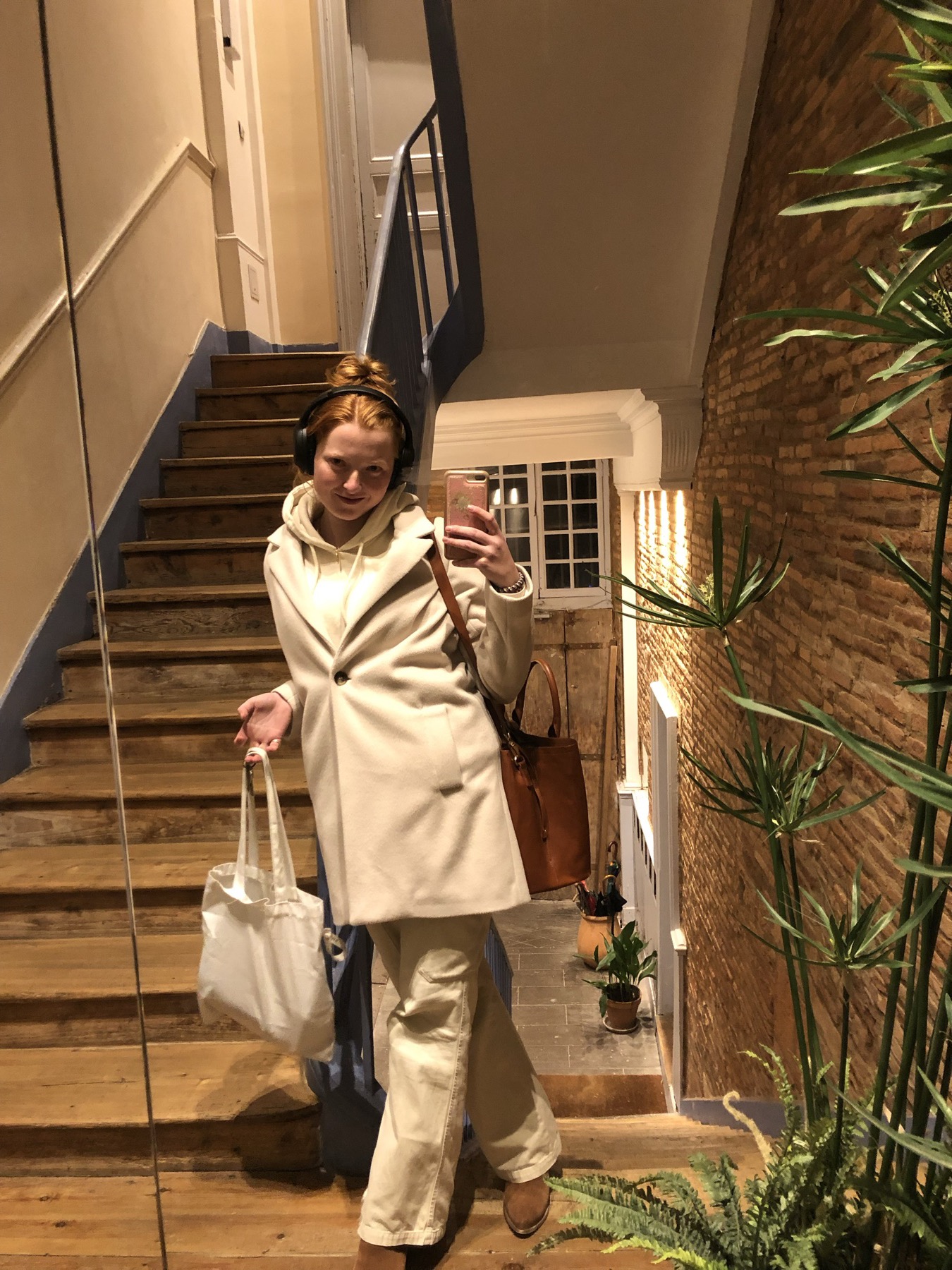 Claire-Catherine in a cream coat on a wooden staircase